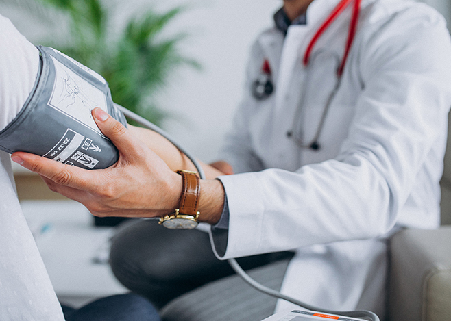 Young male psysician with patient measuring blood pressure